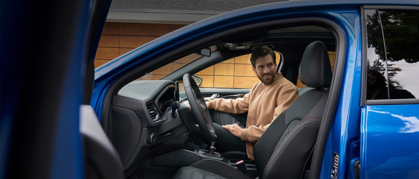 Mann sitzt auf dem Beifahrersitz in einem blauen Ford Focus