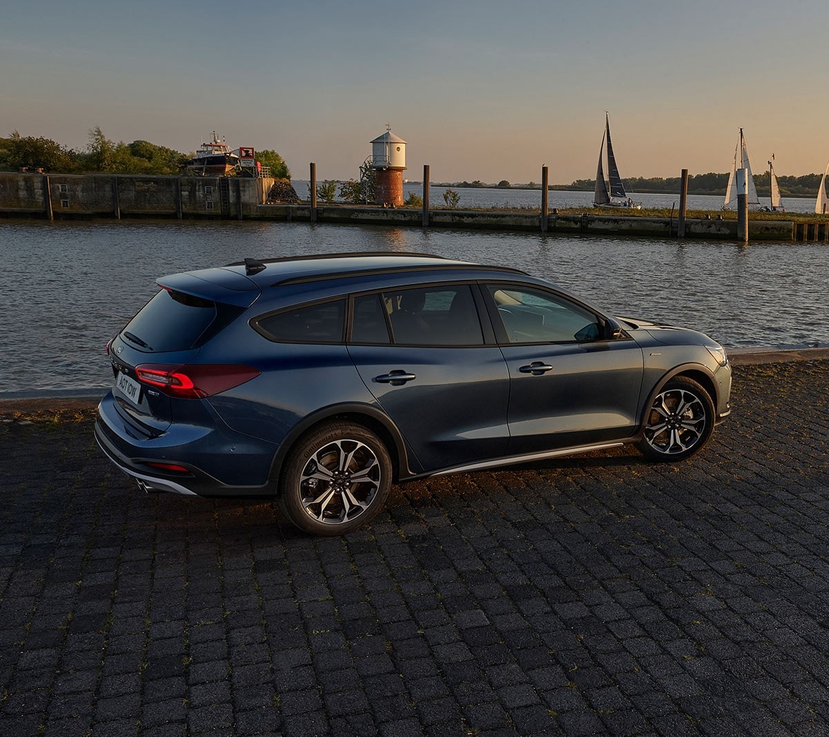 Ford Focus in Blau. Dreiviertelansicht, vor einem See im Sonnenuntergang parkend.