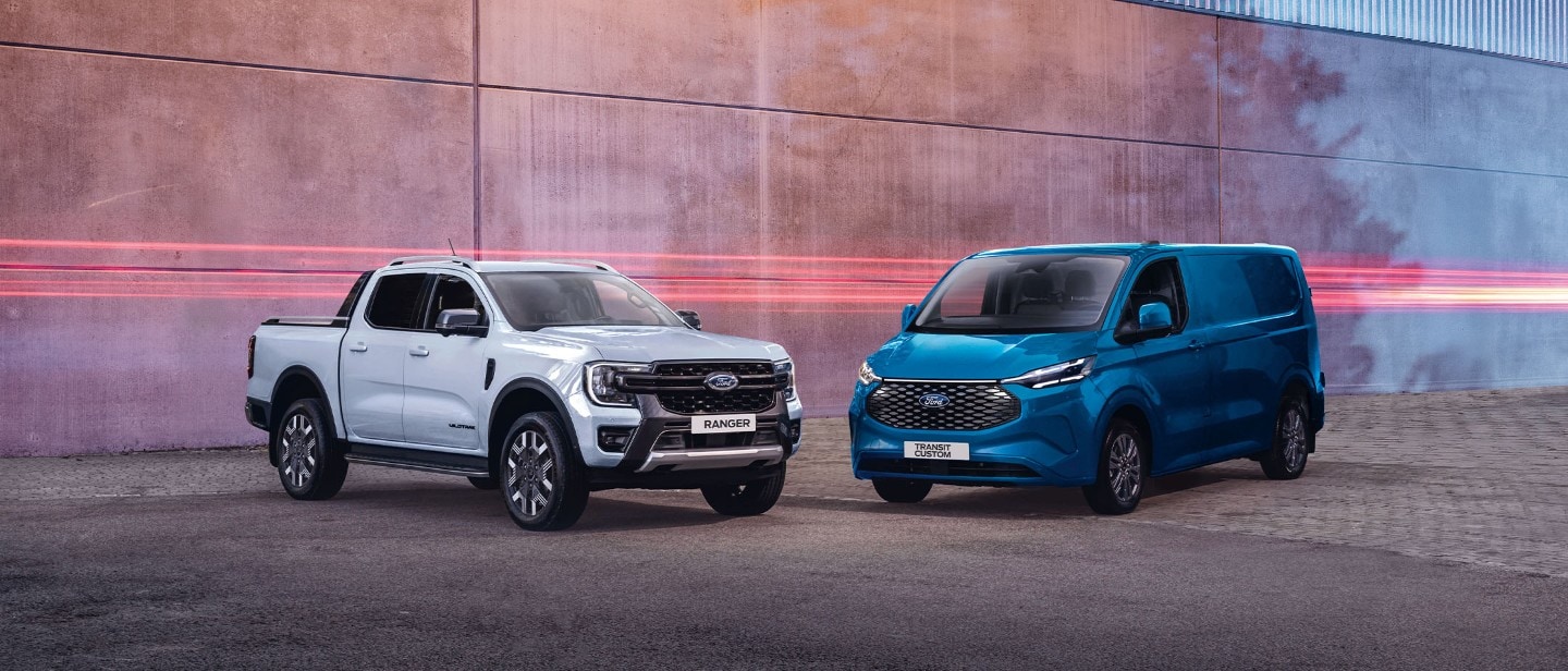 Ford Ranger in Weiß und Ford E-Transit Custom in Blau. Dreiviertelansicht, geparkt vor einer Mauer.