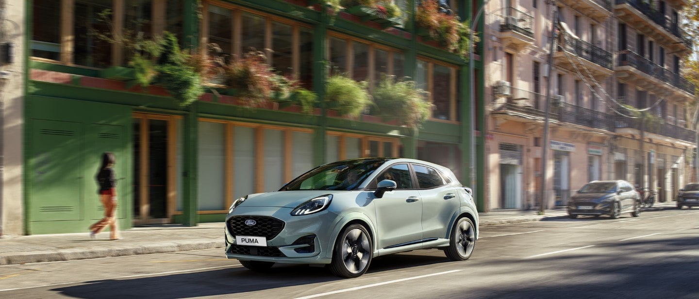 Ford Puma in Grau. Dreiviertelansicht, fährt durch eine Stadt.