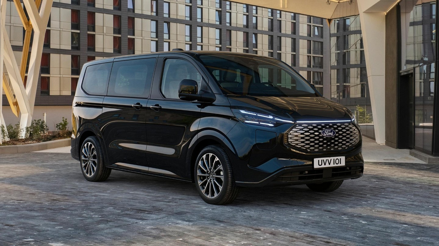 Ford Tourneo Custom in Schwarz. Dreiviertelansicht, vor einem Gebäude geparkt.
