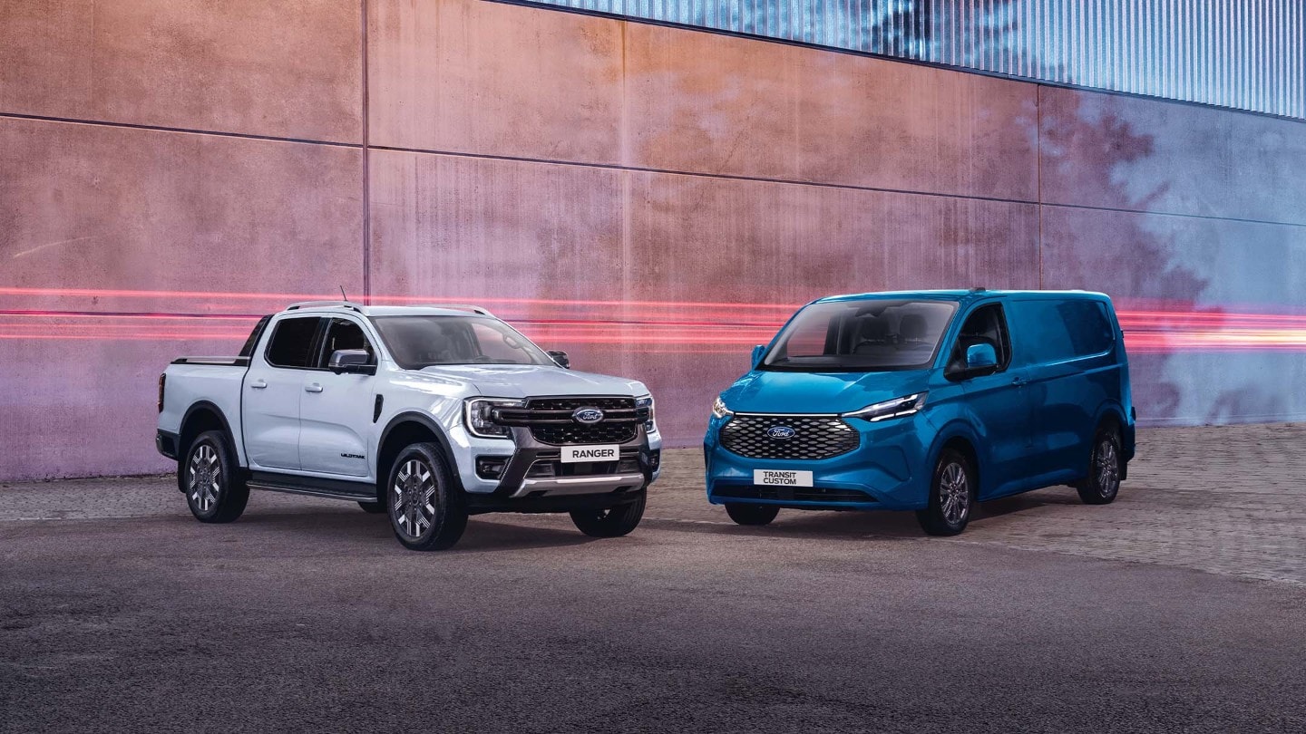 Ford Ranger in Weiß und Ford E-Transit Custom in Blau. Dreiviertelansicht, geparkt vor einer Mauer.