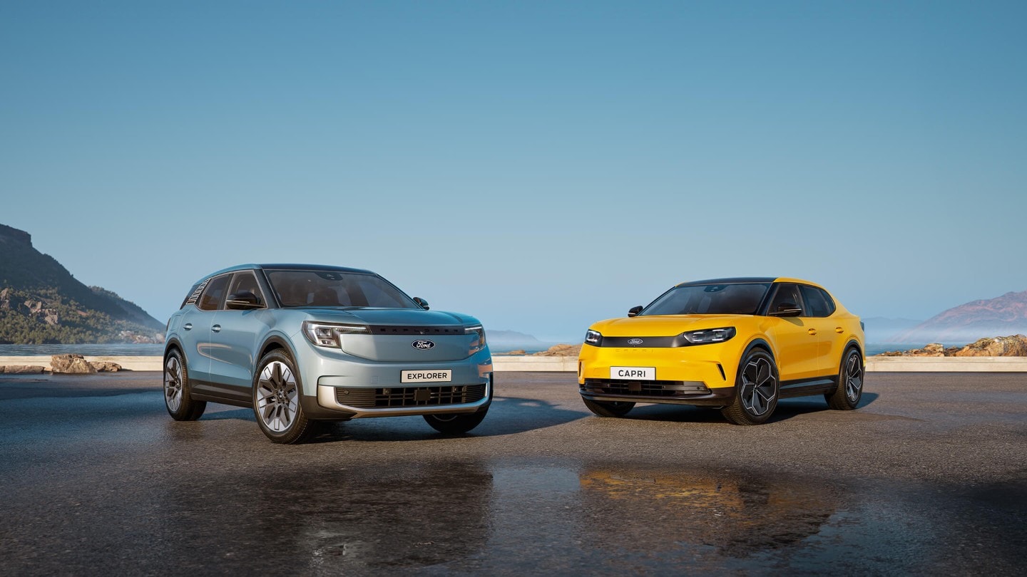 Ein blauer Ford Explorer und ein gelber Ford Capri parken nebeneinander auf einer nassen Straße.