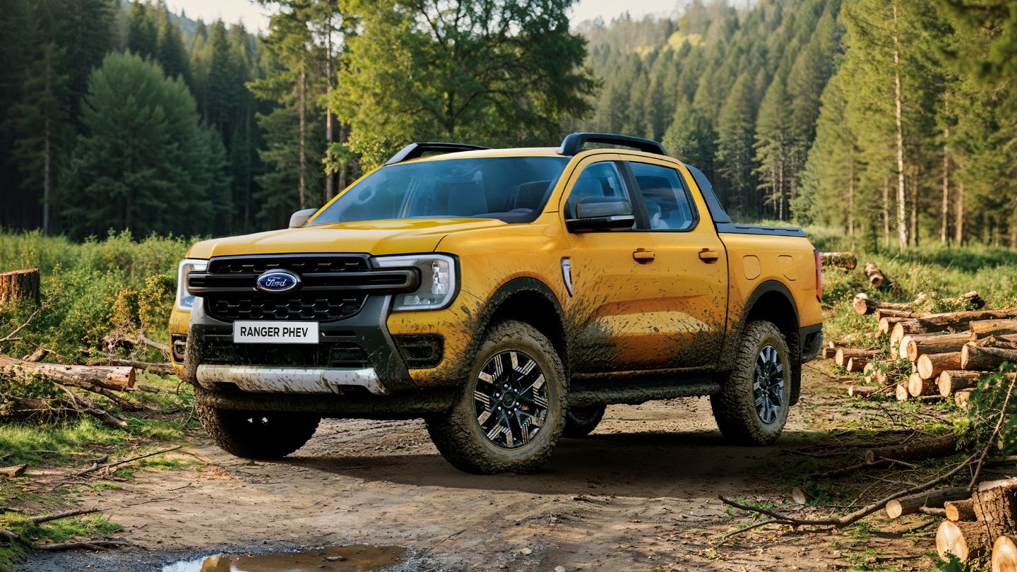 Ford Ranger in Gelb mit Schlammspuren. Dreiviertelansicht, geparkt in einem Wald.