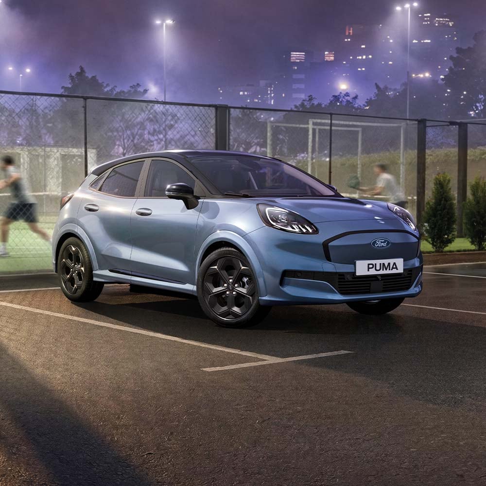 Ford Puma in Blau. Dreiviertelansicht, parkt bei Nacht vor einem Tennisplatz.
