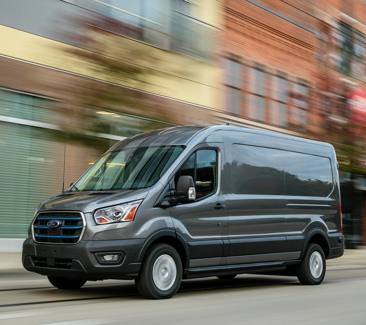 Ford E-Transit In Grau. Dreiviertelansicht, in Bewegung