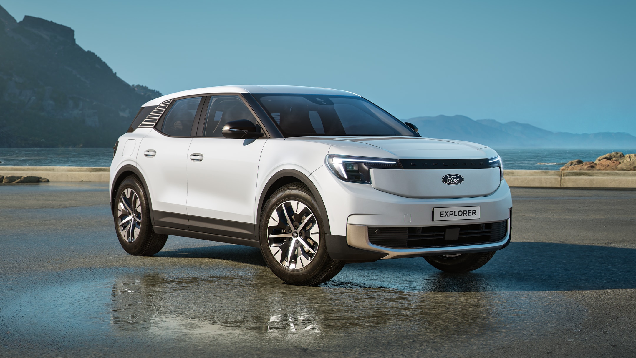 Ford Explorer in Weiß. Dreiviertelansicht, parkt auf einer nassen Fahrbahn mit Hügellandschaft im Hintergrund. 