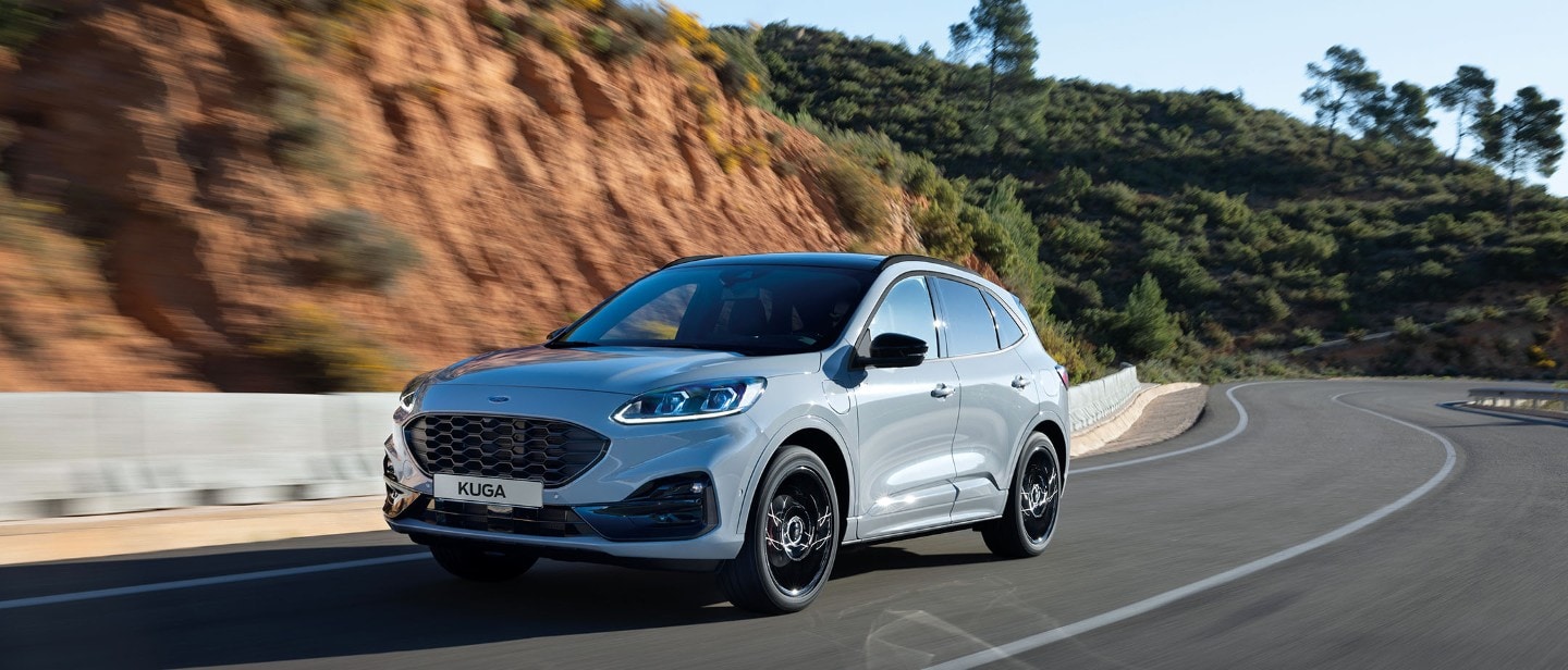 Ford Kuga Graphite Tech Edition. Dreiviertelansicht, fährt in ländlicher Umgebung 