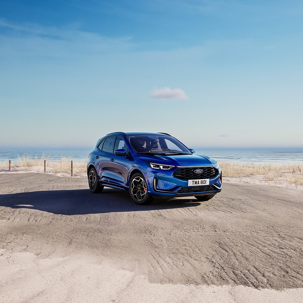 Ein blauer Ford Kuga parkt auf einem Parkplatz neben dem Meer.