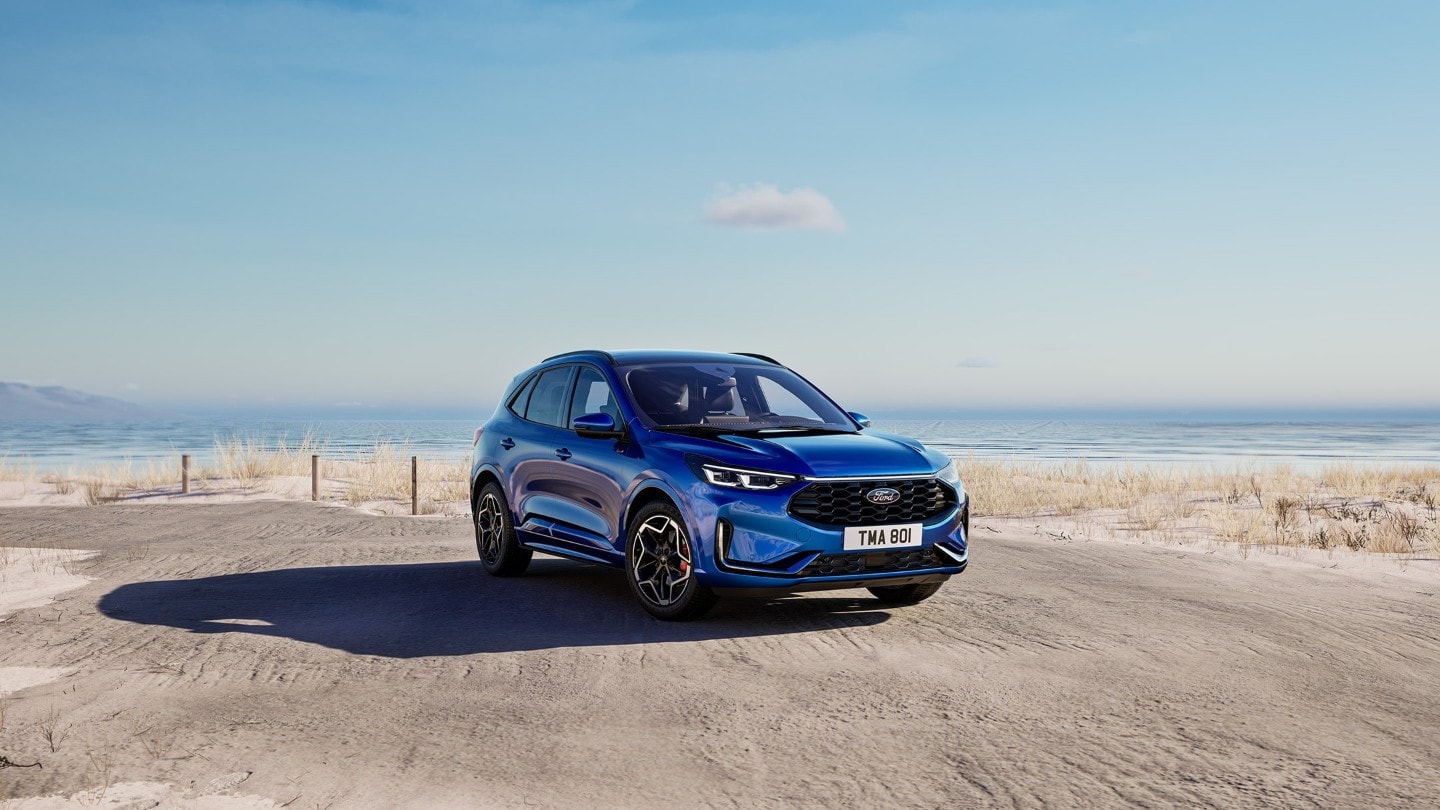 Ein blauer Ford Kuga parkt auf einem Parkplatz neben dem Meer.