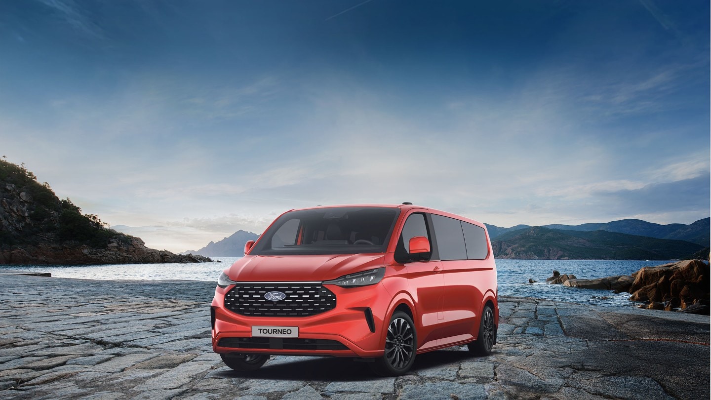 Ford Tourneo Custom in Rot. Dreiviertansicht, parkt vor einem See mit Berglandschaft.