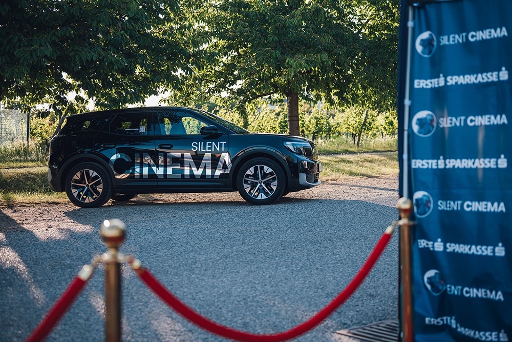 Ford Explorer in Schwarz mit Silent Cinema Logo. Seitenansicht, parkt auf einem Schotterweg.