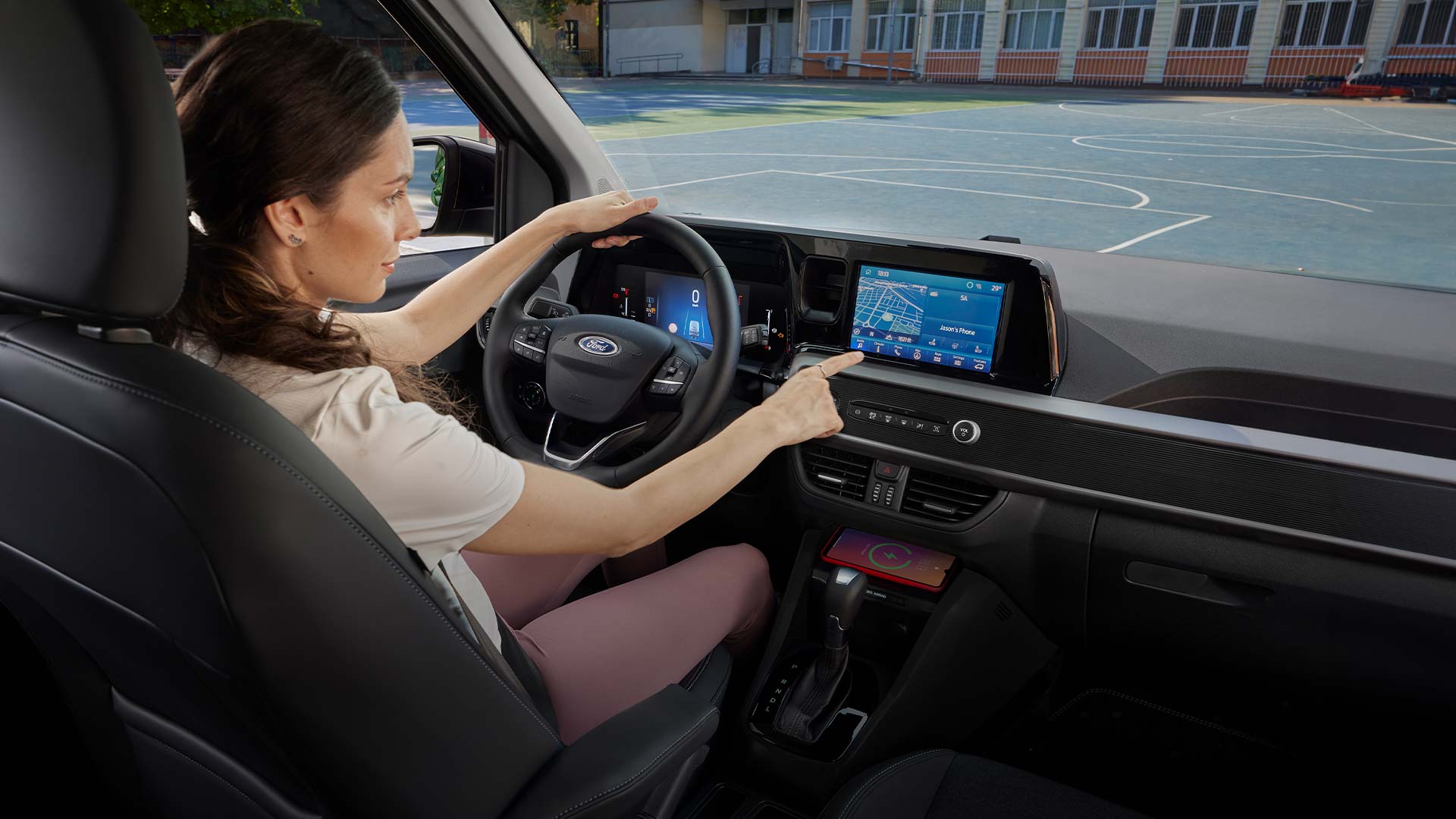 Ford Tourneo Courier Innenraum. Ansicht auf Vordersitz und Armaturenbrett mit Ford SYNC 4-Touchscreen. Frau sitzt im Fahrersitz.