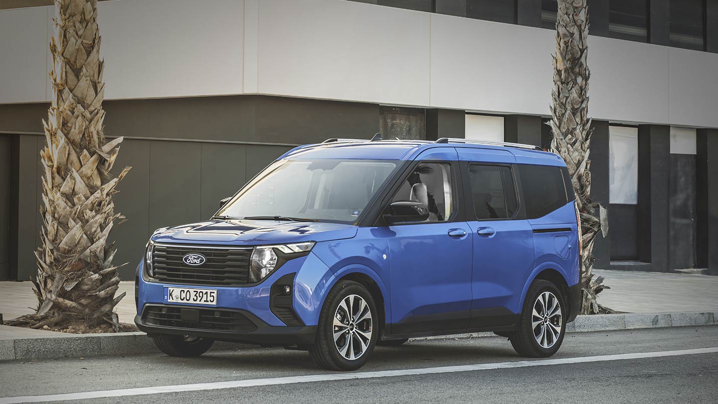 Ford Tourneo Courier in Blau. Dreiviertelansicht, parkt vor auf der Straße vor einem Haus.