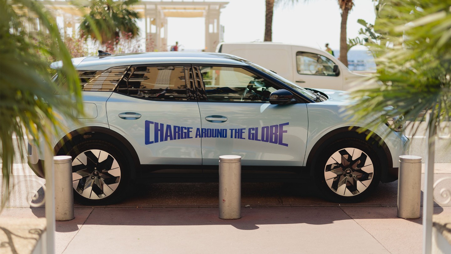 Der vollelektrische Ford Explorer in Blau. Seitenansicht, parkend zwischen Palmen.