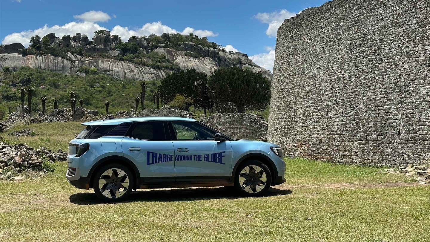 Der vollelektrische Ford Explorer in Blau. Seitenansicht, steht vor einer Ruine mit Hügeln im Hintergrund.