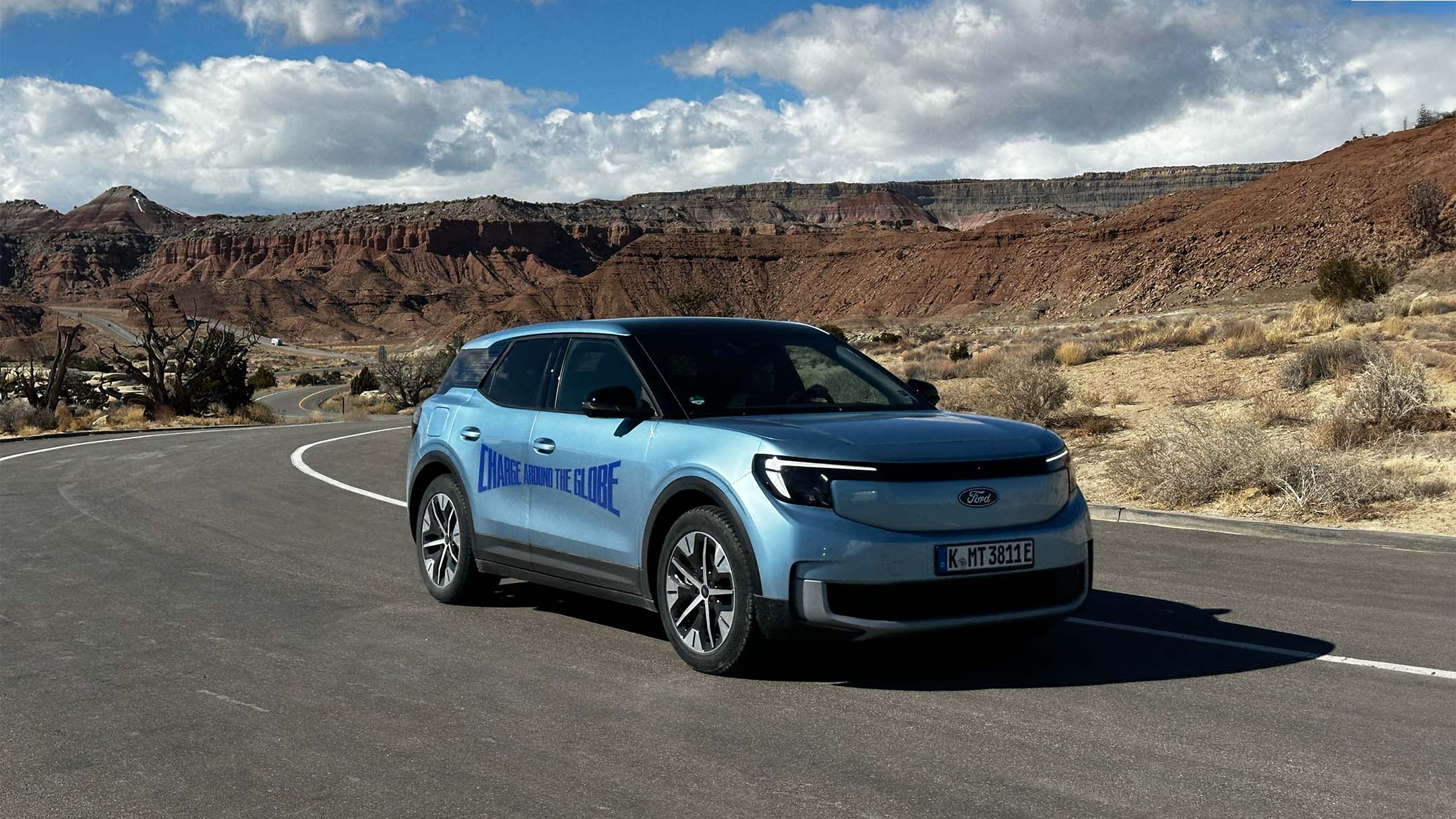 Vollelektrischer Ford Explorer in Blau. Dreiviertelansicht, fährt in einer Wüstenlandschaft.