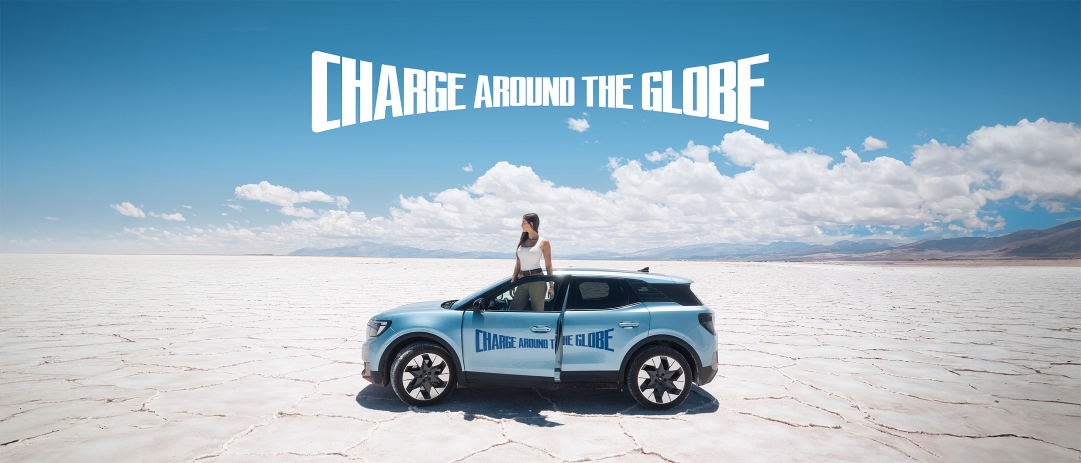 Lexie Limitless und der vollelektrische Ford Explorer in Blau, stehend in einer Wüste. 