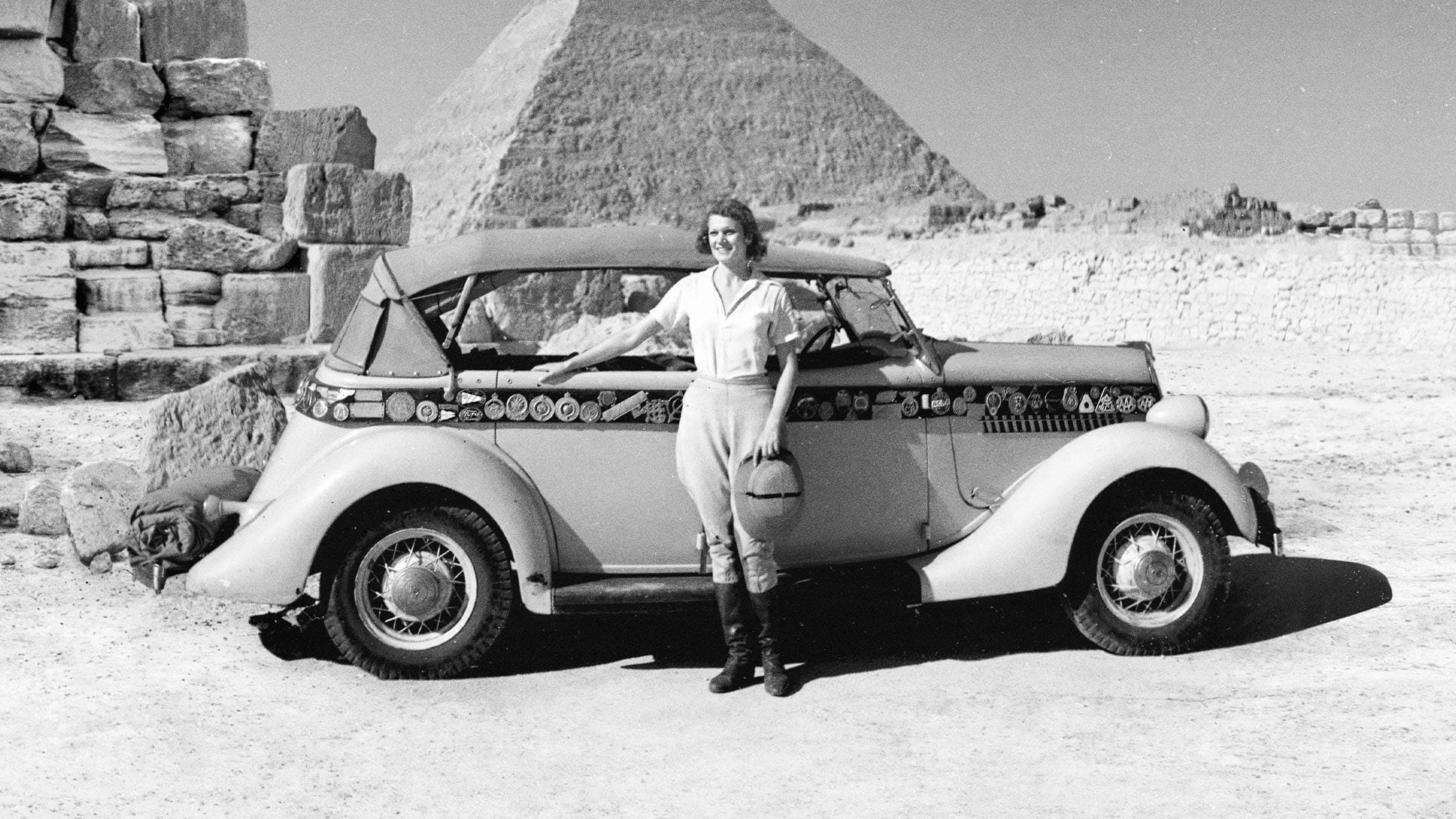 Aloha Wanderwell vor ihrem Ford Model-T stehend, mit Pyramide im Hintergrund