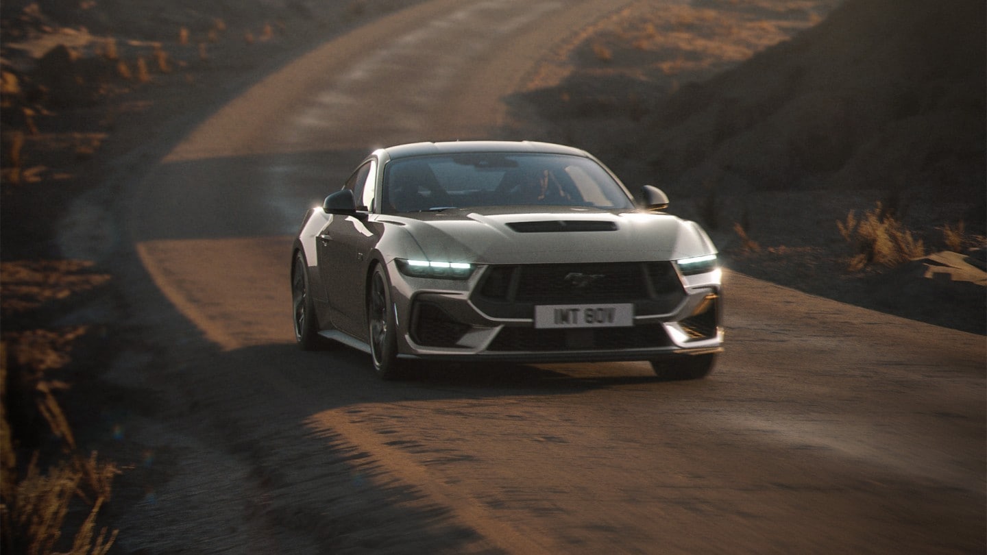 Ford Mustang GT in Grau. Frontansicht, fahrend auf einer unbefestigten Straße.