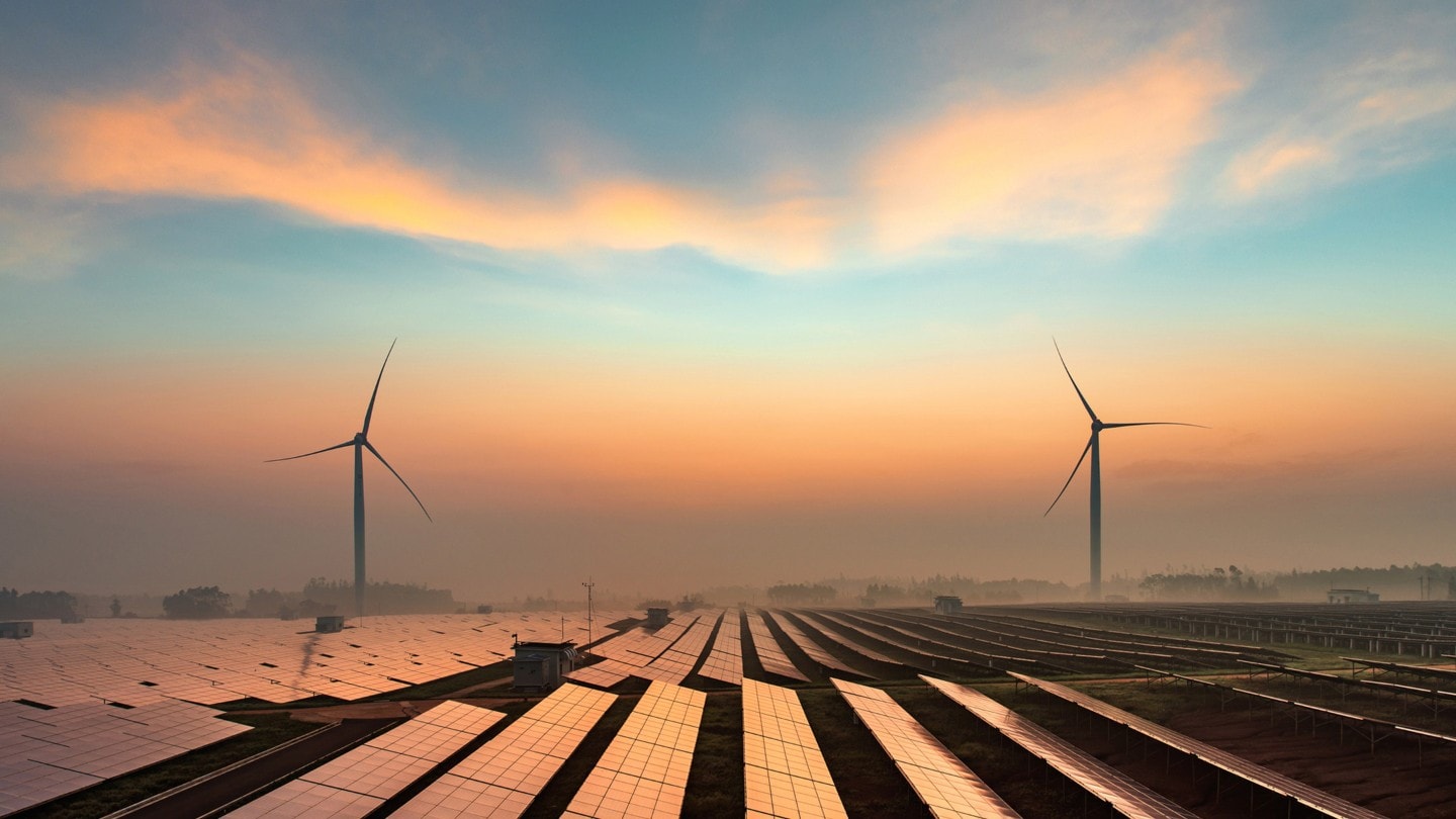 Feld voller Photovoltaik Module mit zwei Windkrafträdern am Horizont