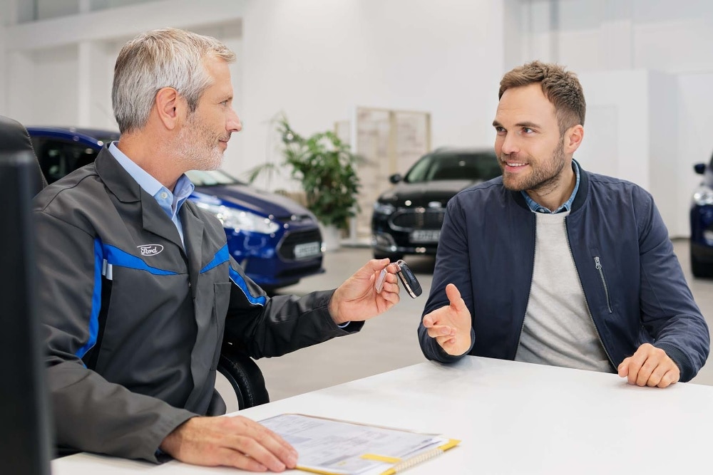 Zwei Männer sitzen an einem Tisch bei einem Ford-Partner