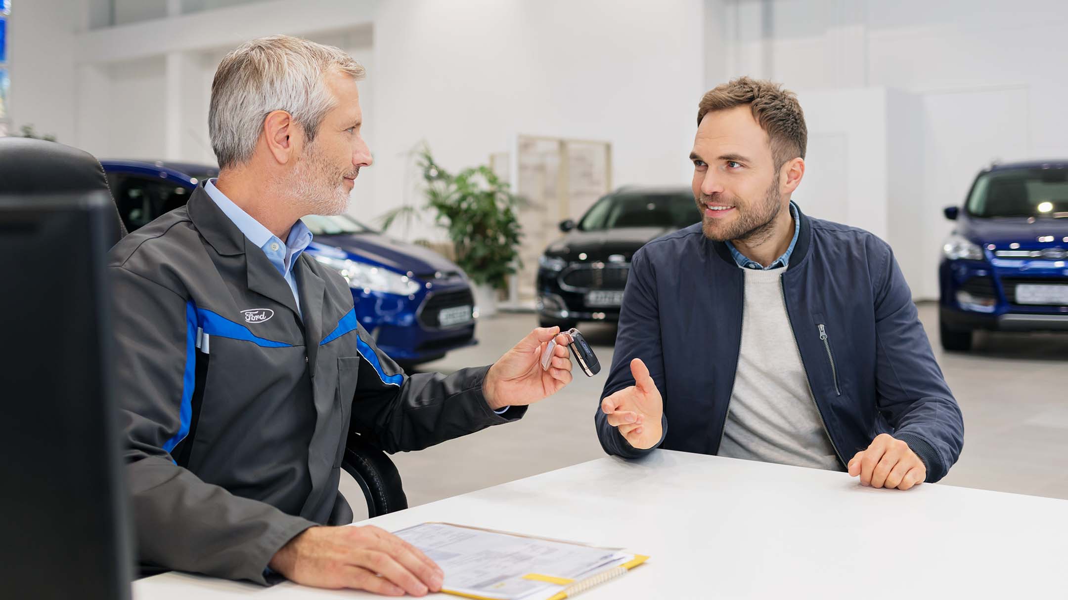 Zwei Männer sitzen an einem Tisch bei einem Ford-Partner