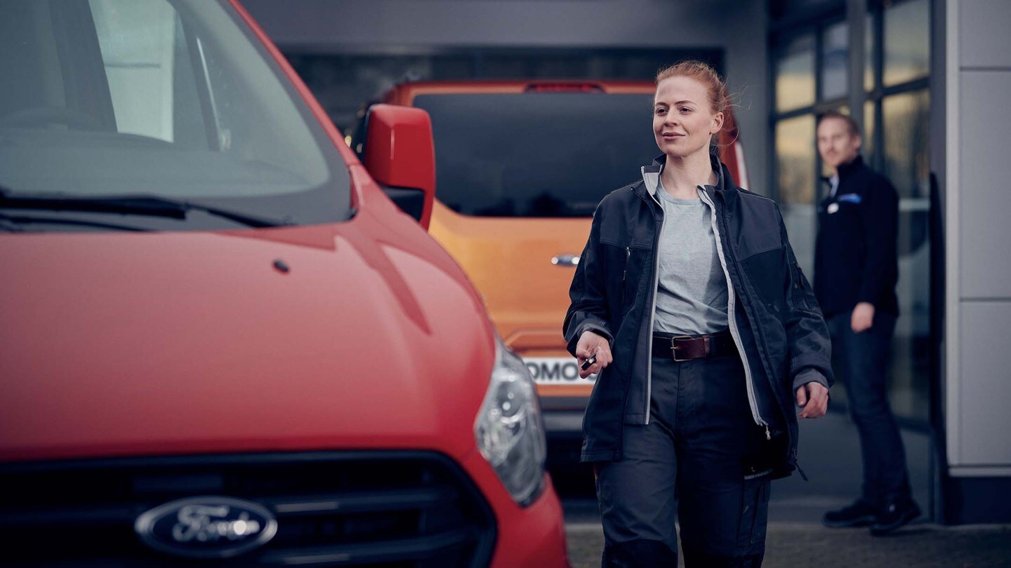 Frau geht zu einem roten Ford Nutzfahrzeug