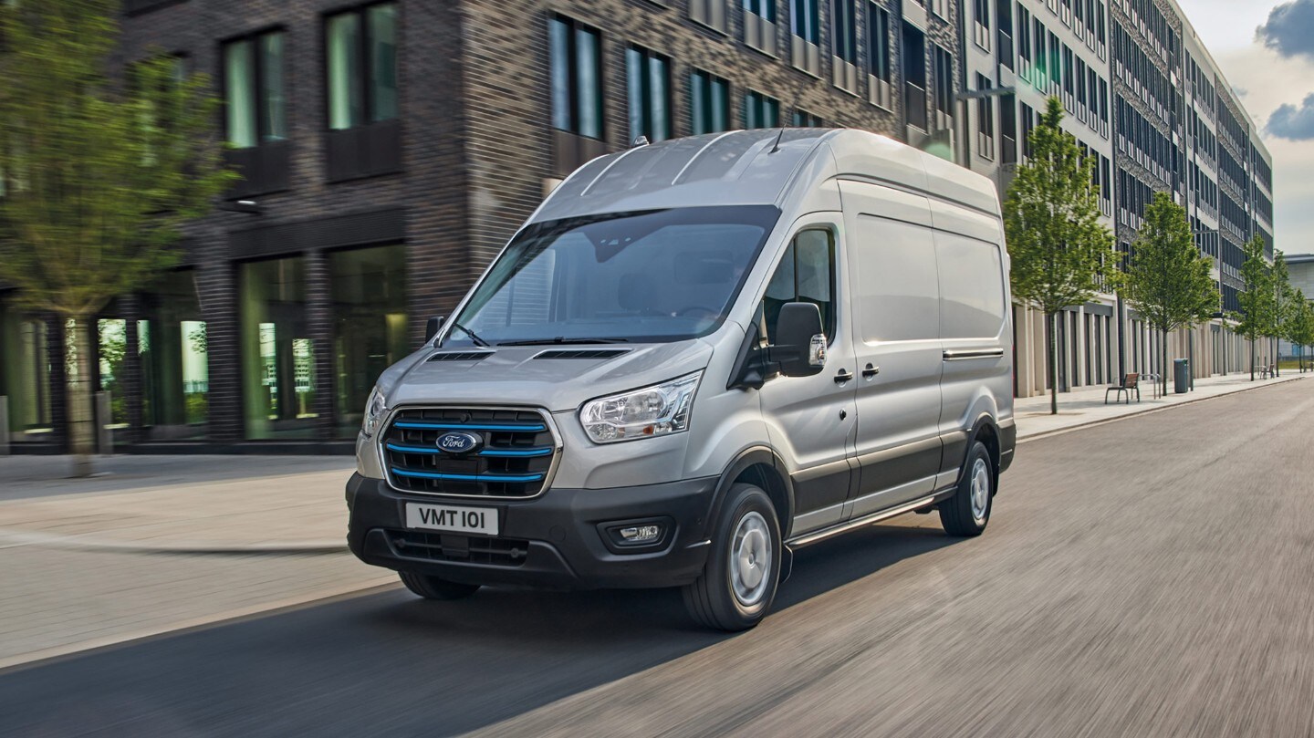 Ford Transit in Silber. Frontansicht, fahrend auf Straße in Stadt