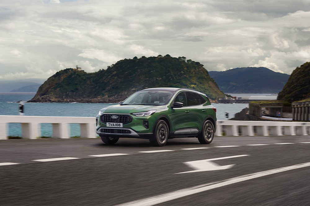 Ford Kuga in Grün. Dreiviertelansicht, fahrend über eine Brücke.