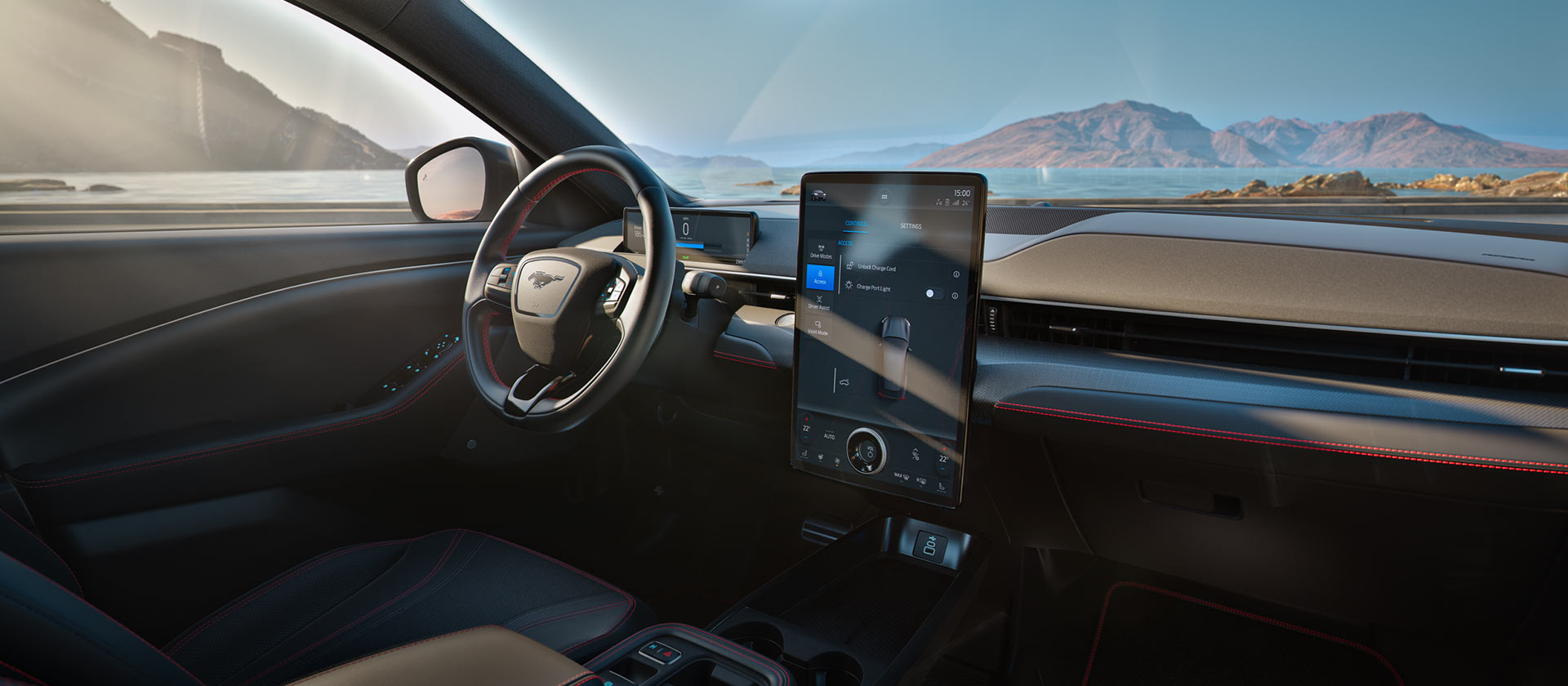 Ford Mustang Mach-E Innenraum. Detailansicht des Lenkrads und Touchscreens mit Blick auf Berglandschaft durch die Windschutzscheibe.