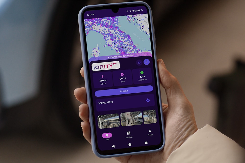 Eine Person hält ein Smartphone mit geöffneter Octopus Electroverse App in der Hand. Am Display werden Ladestationen angezeigt.