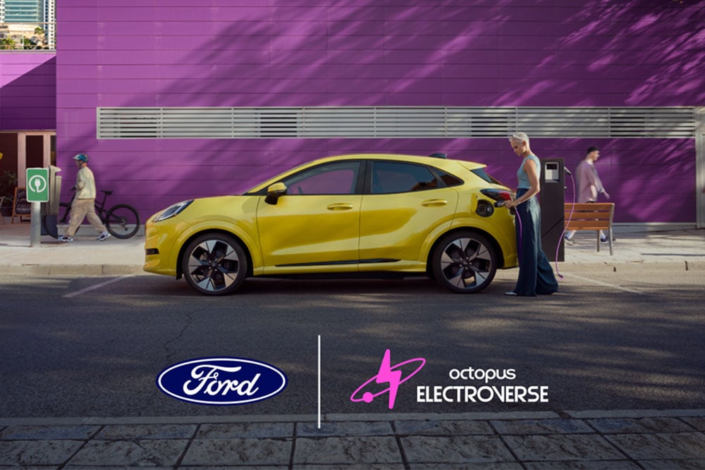 Ford Puma Gen-E in Gelb. Seitenansicht, eine Person schließt ein Ladekabel an einer öffentlichen Ladestation an. Unten ist das BlueOval™ Charge Network x Octopus Electroverse Logo zu sehen.