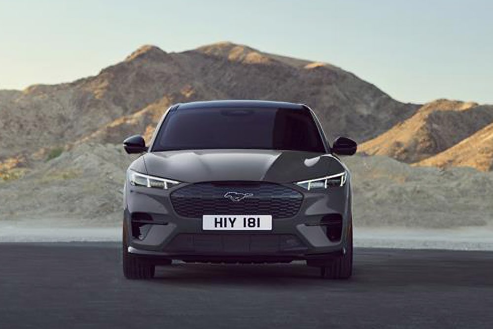 Ein schwarzer Ford Mustang Mach-E. Frontansicht, parkt vor einer Berglandschaft.