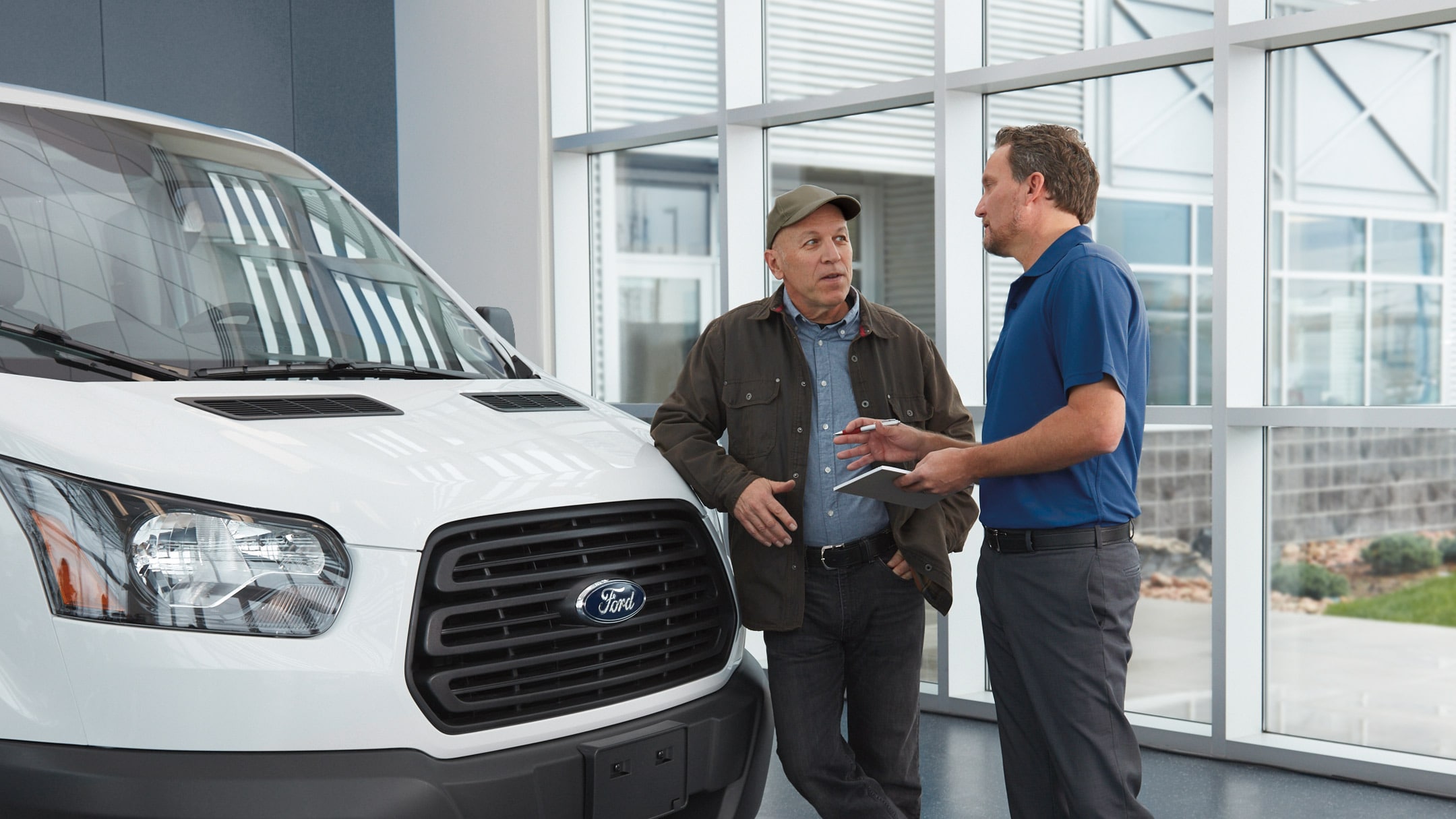 Zwei Männer stehen neben einem Ford Fahrzeug und unterhalten sich