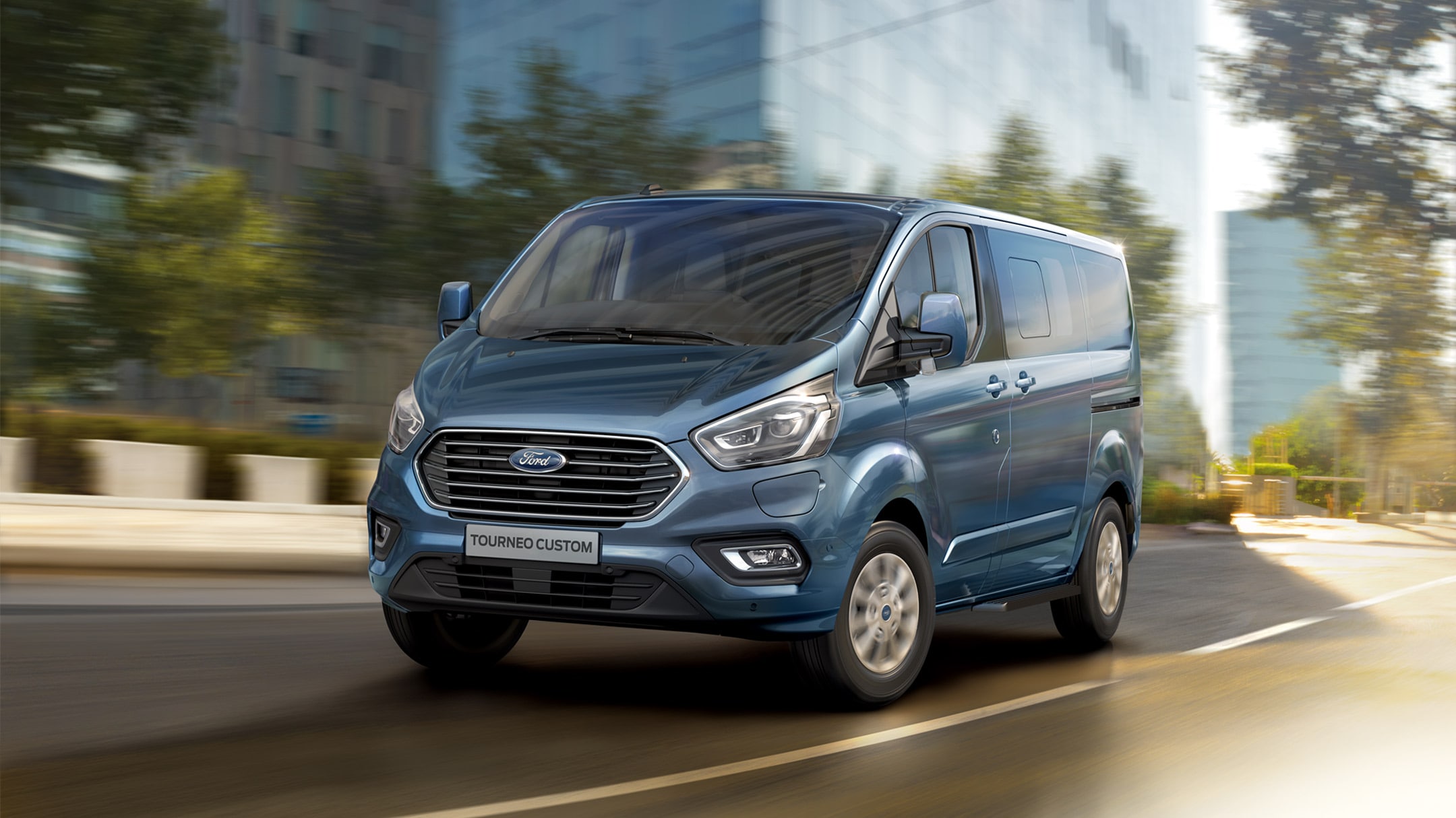 Ford Tourneo Custom in Blau. Dreiviertelansicht, fährt durch die Stadt