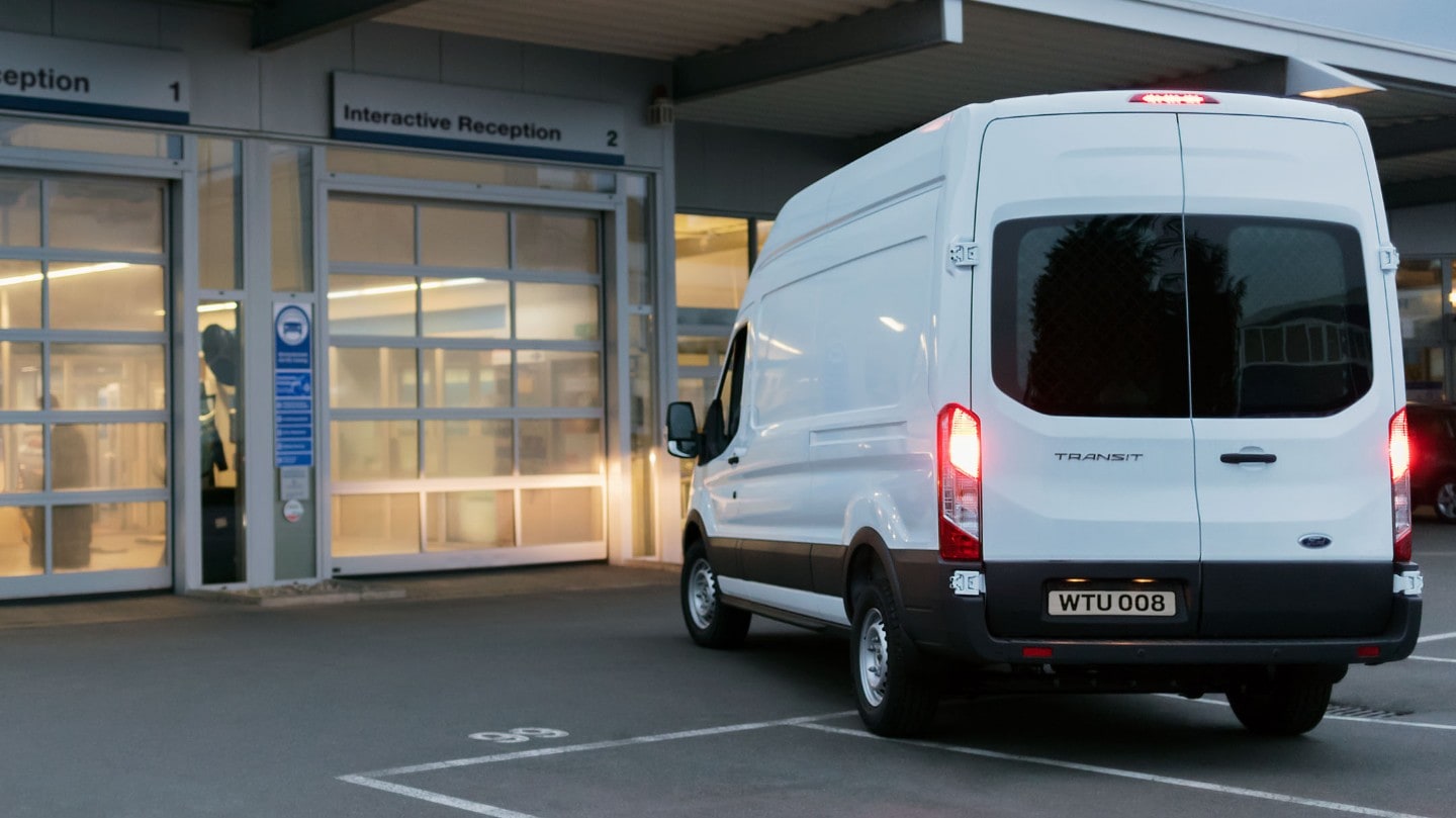 Ford Transit in Weiß. Heckansicht, parkt vor Ford Werkstatt