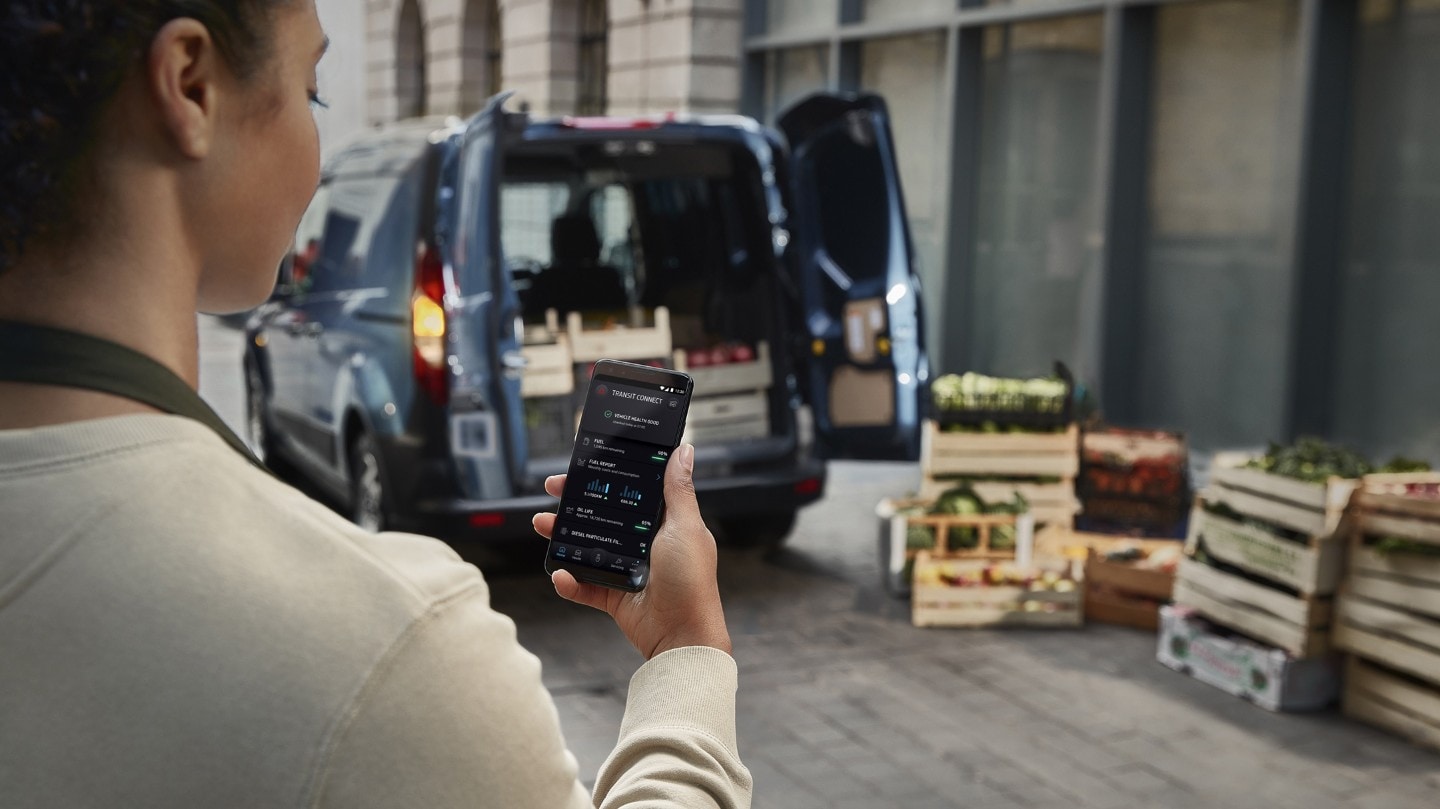 Frau schaut auf ein Smartphone mit geöffneter FordPass Pro App 