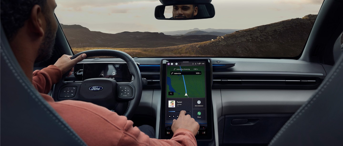 Ford Explorer Innenansicht. Eine Person sitzt auf dem Fahrersitz und bedient den Ford SYNC-Touchscreen.