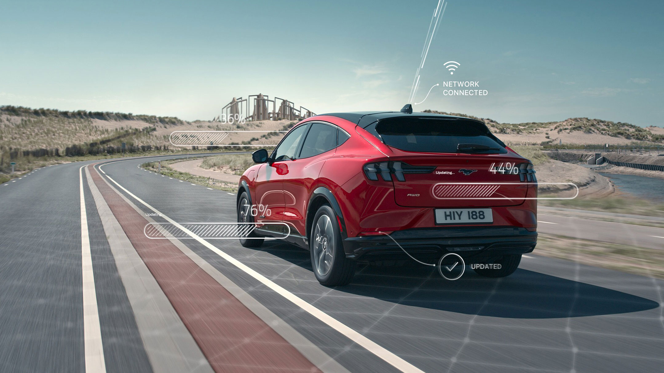 Ford Mustang Mach-E in Rot. Heckansicht, fährt auf einer Landstraße