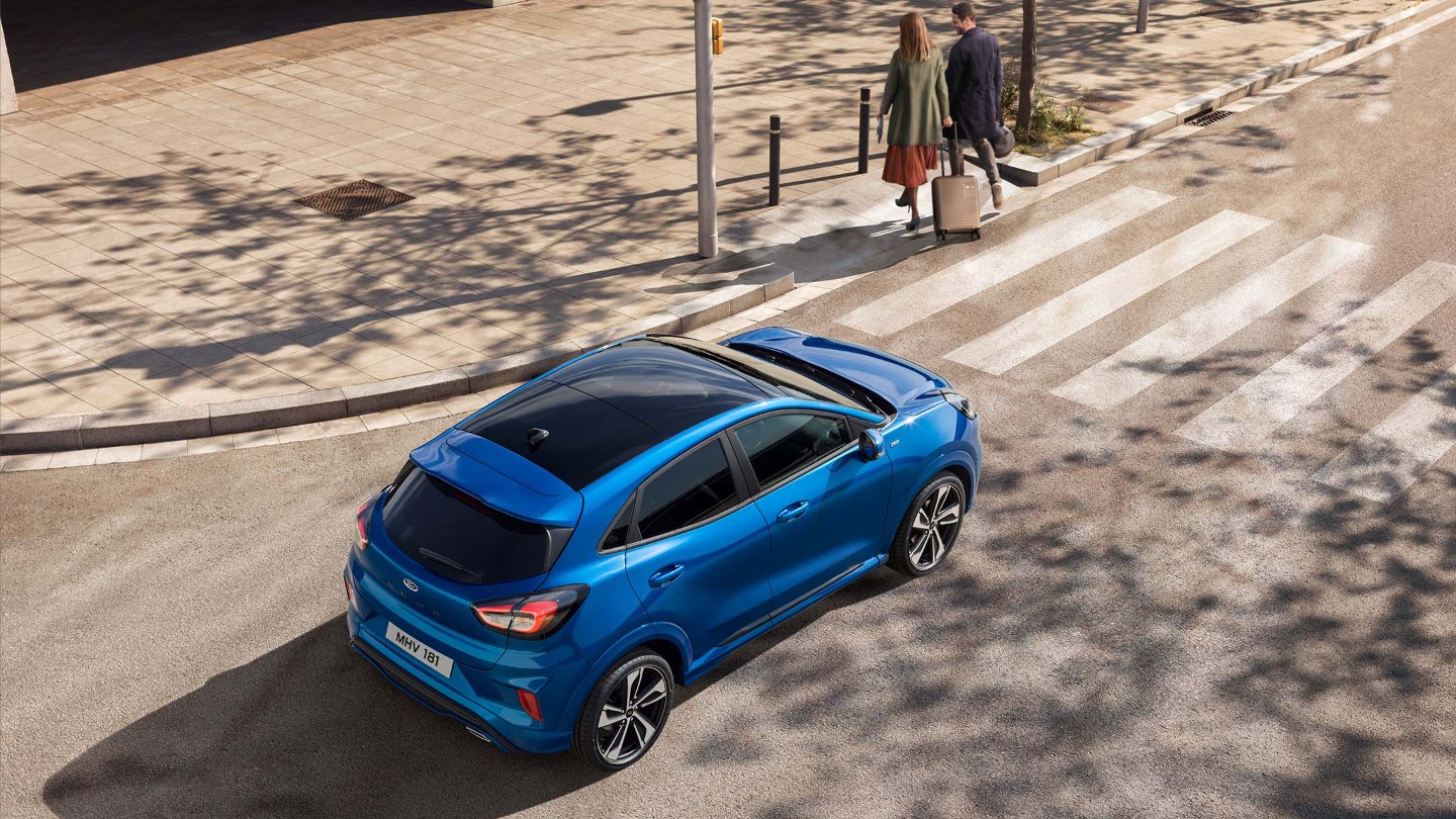 Ford Puma in Blau. Ansicht von oben, hält vor einem Zebrastreifen