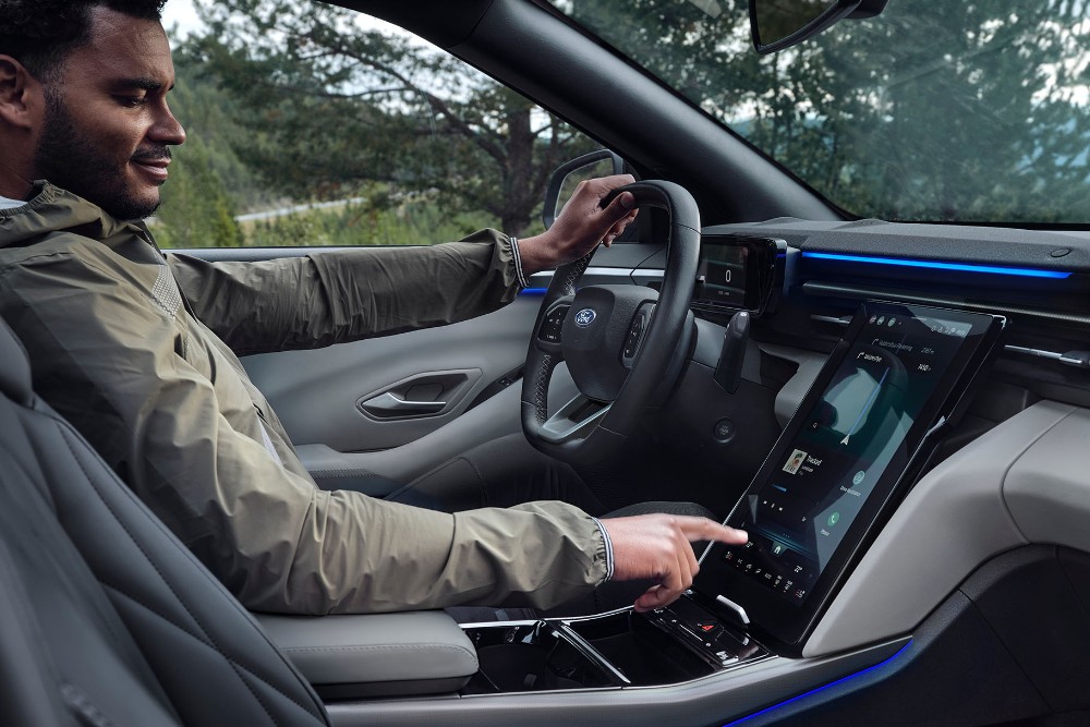 Ein Mann sitzt auf dem Fahrersitz eines Ford Explorer und bedient den großen SYNC Move-Touchscreen.