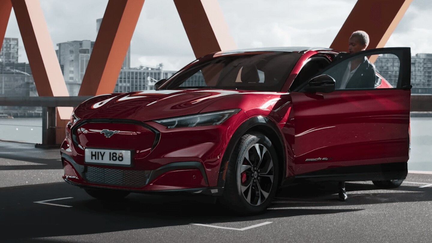 Ford Mustang Mach-E in Rot. Mann steigt in das Auto ein. 