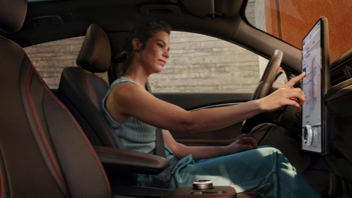 Frau sitzt im Auto und bedient einen Touchscreen