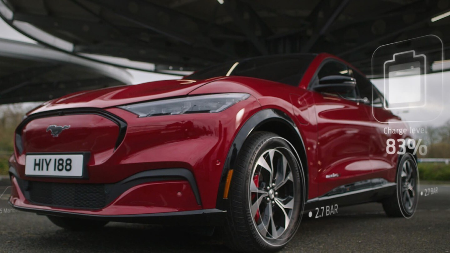 Ford Mustang Mach-E in Rot. Dreiviertelansicht, parkt unter einer Plattform