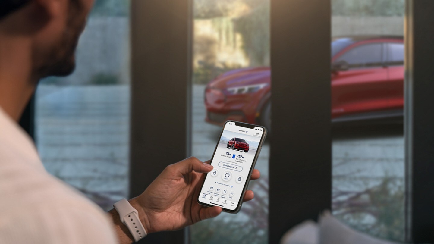 Eine Frau hält ein Smartphone in der Hand und schaut aus dem Fenster.