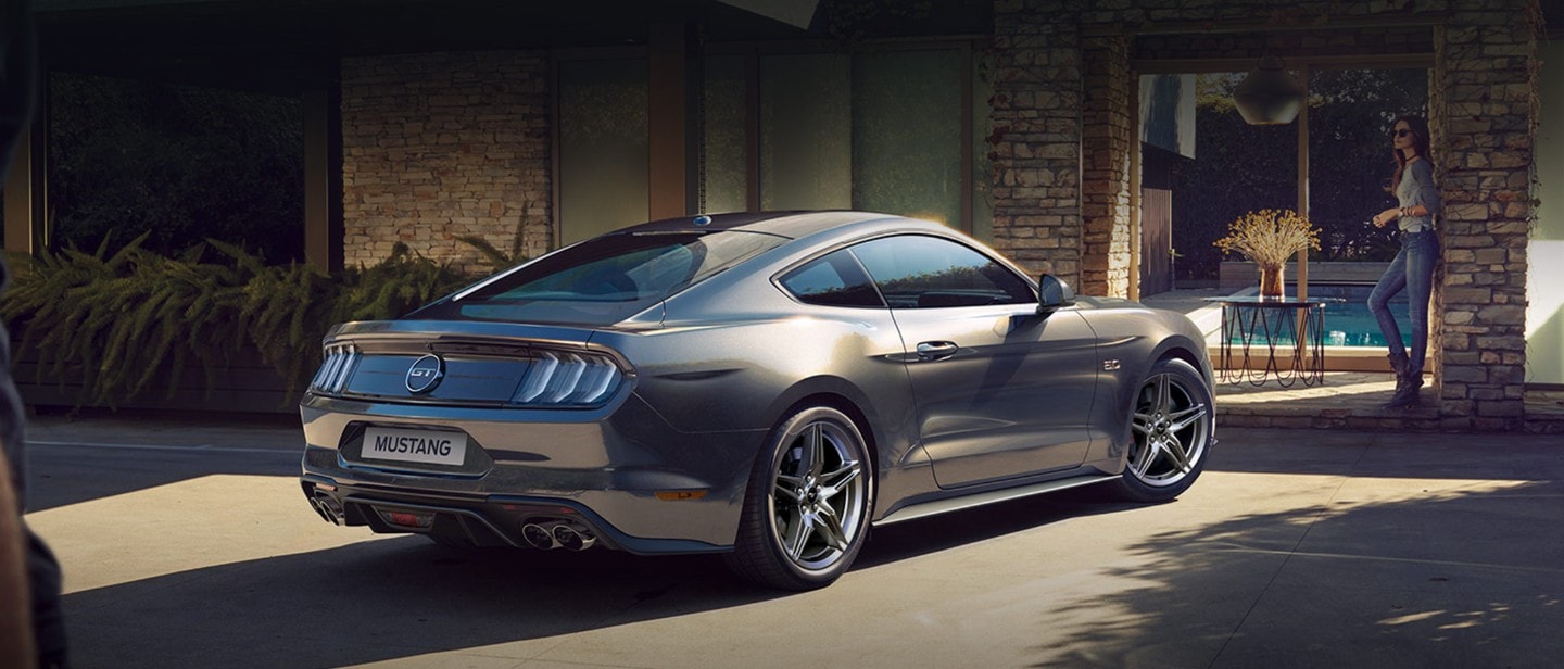 Ford Mustang in Grau. Heckansicht, parkt vor einem Wohnhaus