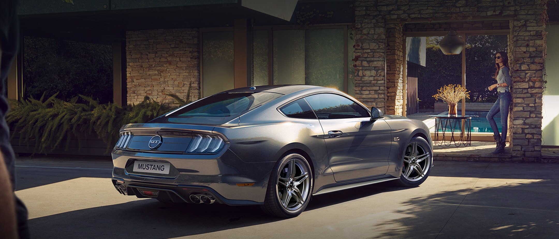 Ford Mustang in Grau. Heckansicht, parkt vor einem Wohnhaus