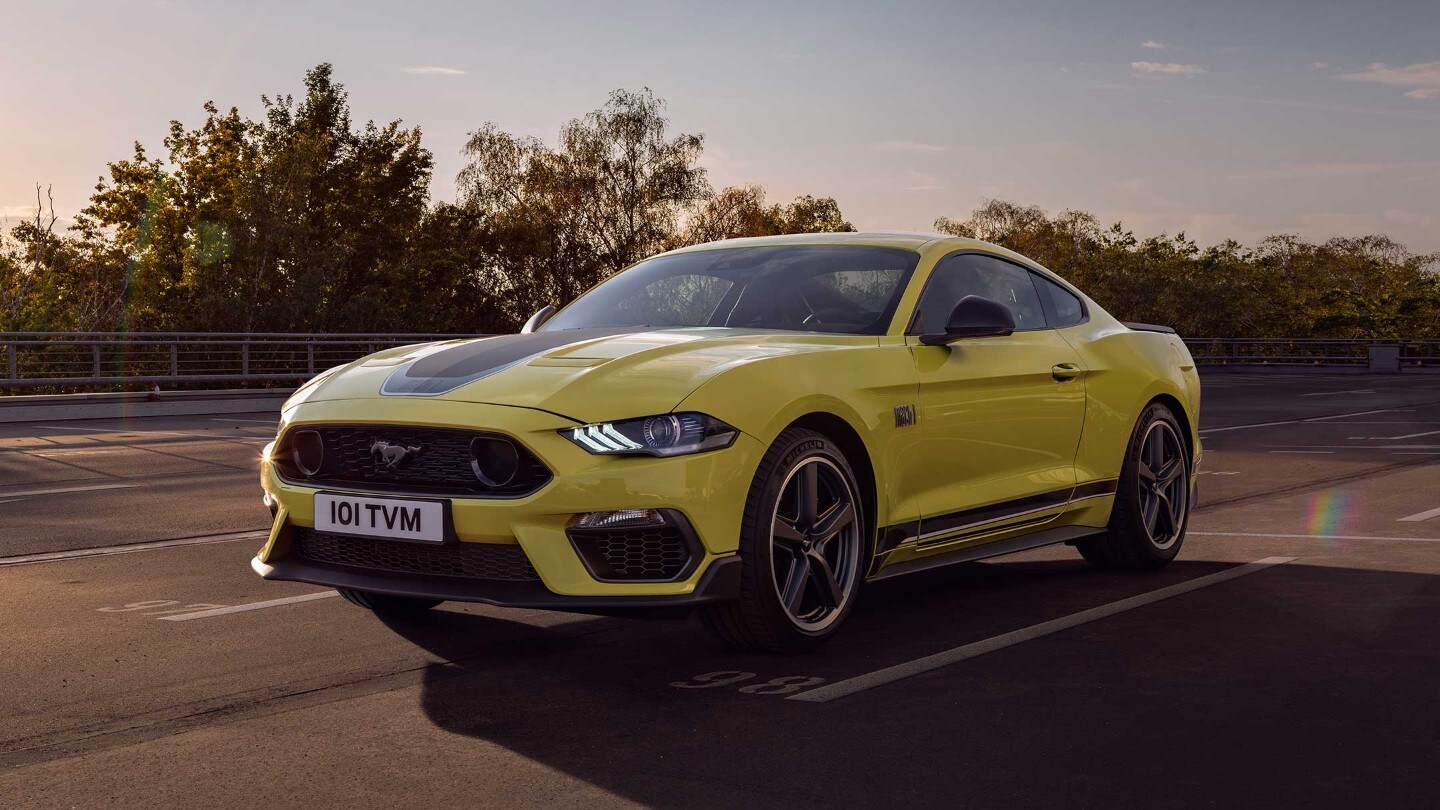 Ford Mustang in Gelb. Dreiviertelansicht, Fahrsituation auf einer Straße. 