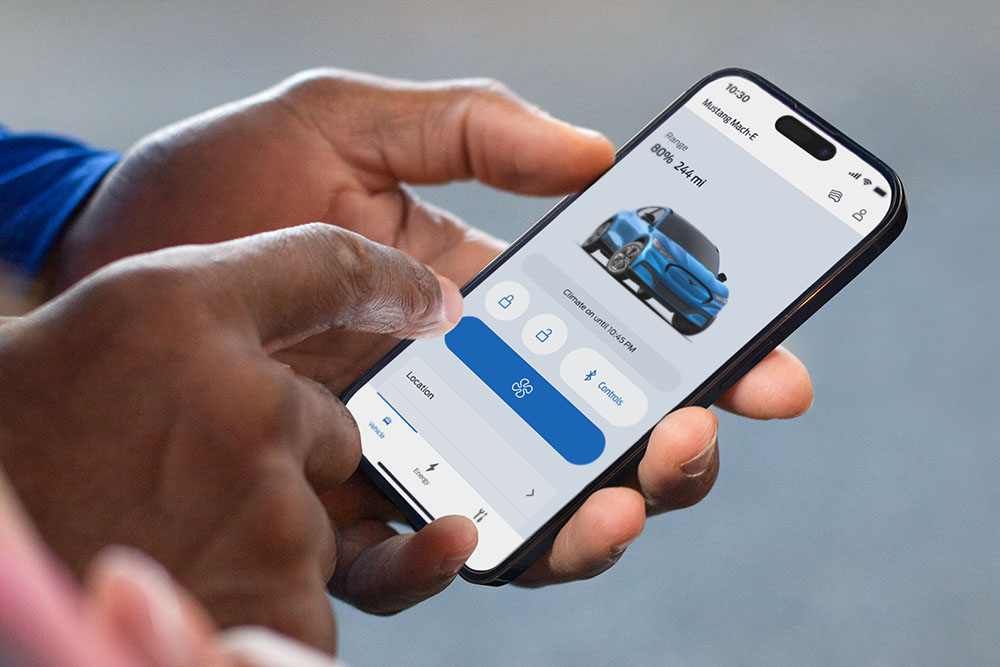 Hand hält ein Smartphone mit geöffneter FordPass App, die eine Grafik eines Ford Mustang Mach-E zeigt.
